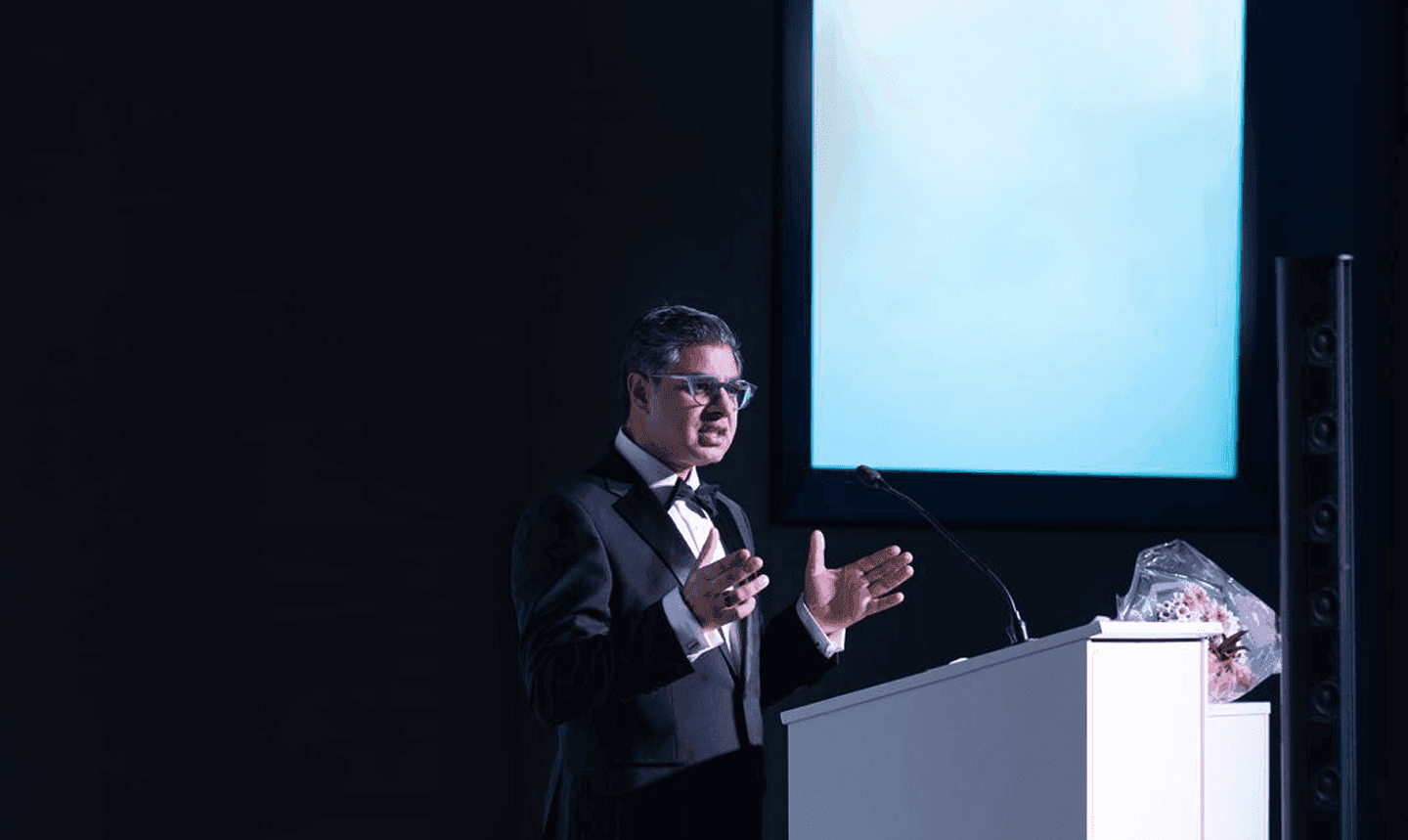 Ash Ali speaking on stage at a global keynote event