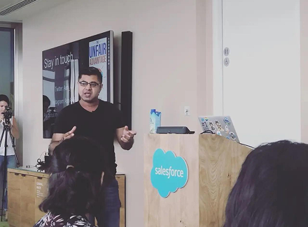 Ash Ali speaking to a team at Salesforce with The Unfair Advantage on screen behind him