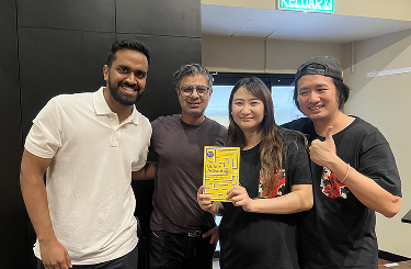 Ash Ali with attendees holding a book